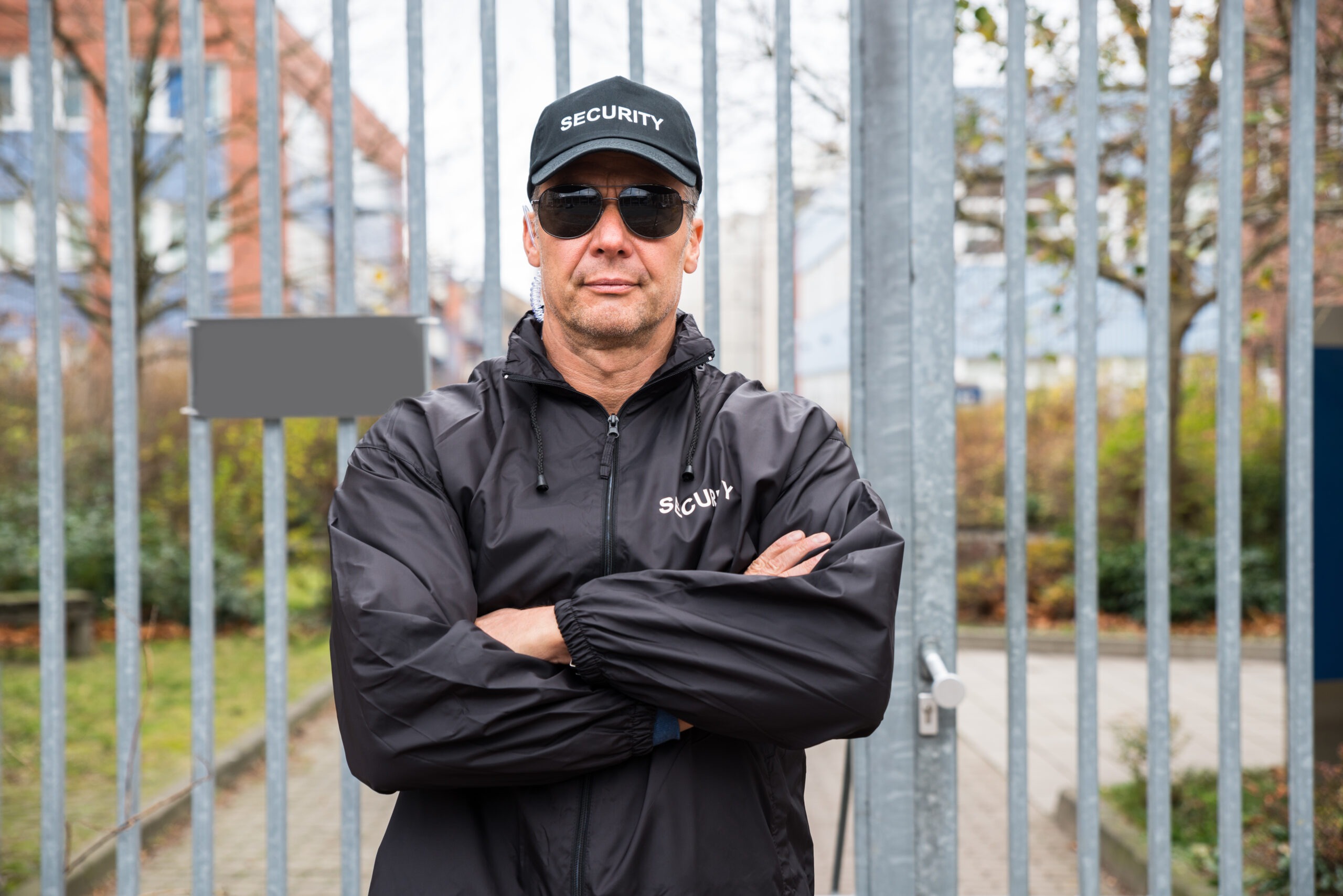 A security guard stands confidently at a gated entrance